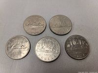 Five Canadian silver dollar coins showing reverse sides with Griffon and voyageur canoe designs.