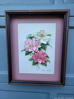 Frontal view of the framed 3D paper tole floral artwork showing pink and white flowers with leaves and signature by Stephen Mullins, mounted on a pink matte in a dark wooden frame without glass.