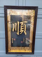 Full view of the framed artwork showing the large gold Chinese character with gold border and inscriptions
