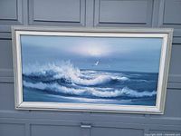 Framed oil painting showing ocean waves and a seagull under a bright sky, signed Taylor.