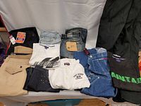 Photo of all items spread flat showing jeans, pants, polo shirts, and t-shirts in various colors and brands.
