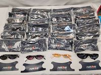 Overview photo showing 30 pairs of Jianlong sunglasses in individual sealed plastic bags arranged in rows with Jianlong branded pouches in front and four sunglasses pairs displayed outside packaging.