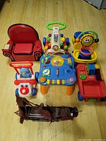 Overview of six assorted kids ride-on and activity toys arranged on floor
