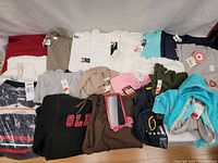 Full overview of all clothing items laid out on red cloth showing variety and quantity.