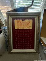 Full view of ornate silver/metallic frame with burgundy quarter collection display featuring US map and 50 coin slots.