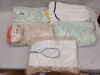 Five new mop heads in original packaging showing various colors and material types.