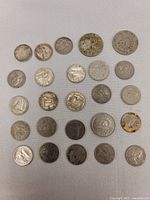 Top view of 27 Canadian coins arranged in rows on a light background, showing wear and tarnish typical of circulated coins, including a coin with rust.