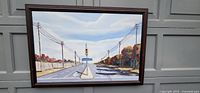 Full view of framed painting depicting Birchmount Road scene with traffic light, street sign, power lines, trees and blue sky.