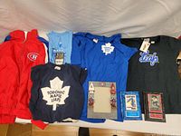 Front view of all items in the lot including jackets, shirts, hockey cards, and framed memorabilia