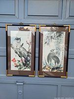 Both framed paintings displayed side by side on a garage door, showing full compositions and framing style.