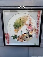 Front view of vintage framed Chinese shell art featuring two peacocks and vibrant shell floral decorations on a circular base with red and black Chinese calligraphy on the borders.