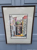 Full view of framed picture of urban alley street with colorful buildings and hanging laundry.