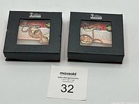 Two black boxes with clear lids showing the necklace sets inside, boxed presentation