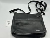Front view of black Danier leather crossbody bag showing pebbled leather texture, adjustable strap, and logo.