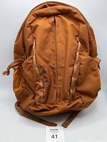Front view of orange Patagonia backpack showing front zippered pocket and Patagonia branding.