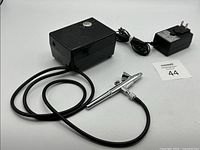 Photo of the airbrush set showing airbrush, compressor, and power adapter together on a white background.