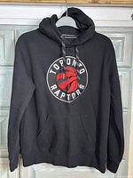 Front view of black Toronto Raptors hoodie showing logo and front kangaroo pocket