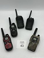 Five assorted walkie talkies on a white background, showing front view with buttons and displays.