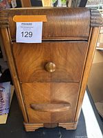 Front view of the nightstand showing two drawers and wood grain finish with some wear.