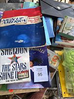 Photo showing a pile of Pee-Chee folders, paperback and hardcover books, and documents arranged in a box.