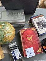 Photo showing the globe without its base, set of hardcover books including 'How Things Work' and a vintage British butterflies and moths book, along with 'The Black Reconstruction in America' book.