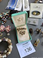 Turquoise jewelry box with five gold-tone decorative stickpins and surrounding bracelets and earrings.