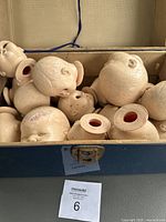 Top-down view of blue hard-shell trunk interior filled with off-white plastic doll heads