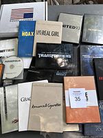 Photo showing a mix of DVD screeners in plastic cases and cardboard sleeves including House of Cards, Hoax, Lars and the Real Girl, United 93, Factory Girl, Transformers, Persepolis, Not There, Romance and Cigarettes.
