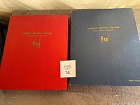 Red and blue notebooks placed side by side showing covers with gold embossed text and logos.