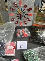 Las Vegas themed clock with red dice as hour markers and colorful clock hands. Several poker chips in plastic bags nearby along with decks of playing cards.