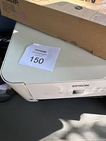 White Epson ET-2720 printer with controls and box visible on top