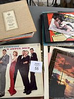 Photo showing a box of assorted vinyl records with some covers damaged, including Ray Conniff album on top.
