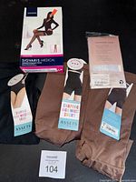 Displays all items in lot: two brown and one black shaping briefs and shorts, with Sigvaris Medical hosiery box