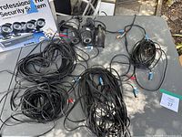 Overview of eight Swann security cameras (black bullet design) with attached cables spread on a table, showing condition and wiring.