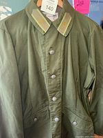 Front view of the olive green Swedish military field jacket with buttons and insignia on the collar.