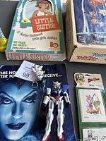 Photo showing Little Sister paper dolls box with vintage Raggedy Ann & Andy mobile packaging, blue and white robot kaleidoscope toy, and Duck Tales Christmas gift tags in original packaging.