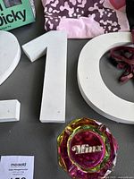 Close-up of white wooden numbers '210' and Minx multicolored glass ashtray