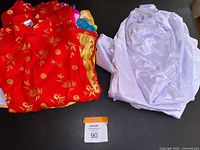 Red and lavender Ao Dai outfits folded; tops and bottoms visible