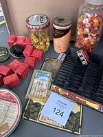 Overview of all items in lot including jar with Bakelite dice, vintage buttons jar, vintage film packs, and some packaged items on cardboard surface