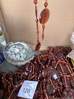 Photo showing brown faceted vintage beads with oval and cylindrical shapes, abalone shell bowl filled with smaller shells and rocks