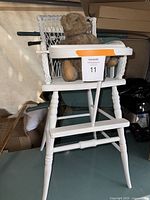 Full view of white vintage high chair with antique plush bear seated in it.