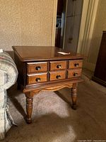 Full view of Bassett side/end table showing top, six drawers with round knobs, and front turned legs with curved apron.