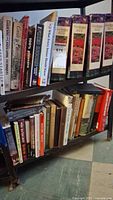 Two metal shelves filled with hardback books. Top shelf includes gardening books, binders, and other general interest titles.