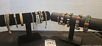 Overall view of the bracelets displayed on two black stands showing the variety and number of bracelets in the lot.