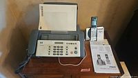 Picture showing entire fax machine with phone handset and manuals on top