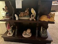 Overall view of wooden shelf displaying all figurines including animals, gnome, lighthouse, and child figure