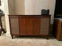 Front view of The Fisher Philharmonic console stereo showing wood cabinet with woven speaker grills and mid-century modern design.
