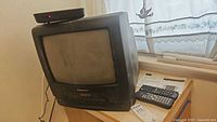 Panasonic 13-inch black CRT TV/VCR combo showing front angled view with remote controls and converter box on top.