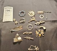 Full overview of all 13 pins and brooches laid on a flat surface showing variety of shapes and designs