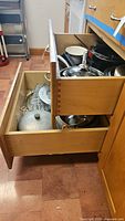 Top drawer with Wear Ever aluminum pots and lids inside wooden drawer